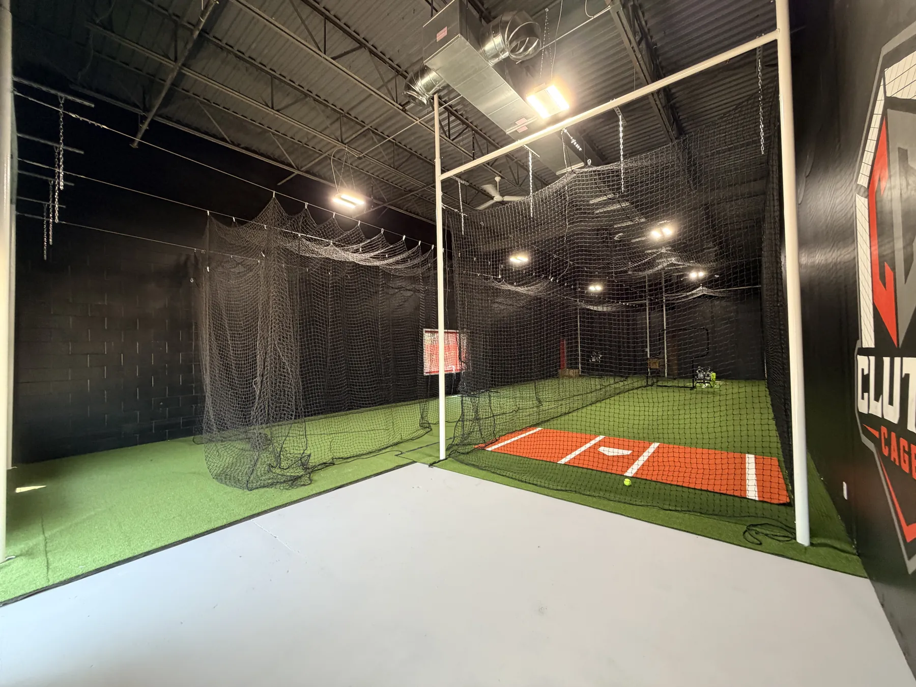 Inside Clutch Cages — both hitting lanes, turf, and the Clutch Cages mark on the back wall