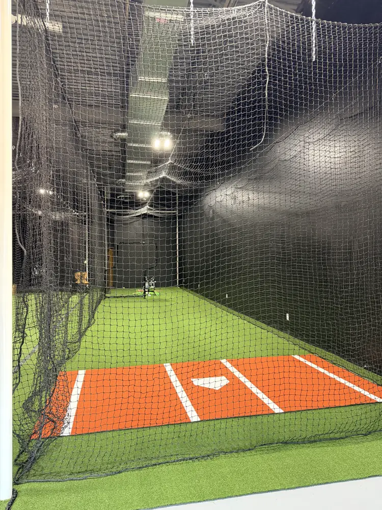 Home plate end of a hitting tunnel with the orange turf strip